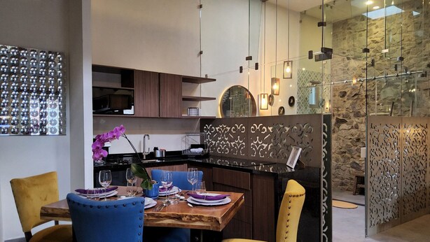 Eine moderne Küche mit Essbereich, ausgestattet mit einem Holztisch, blau-gelben Stühlen und einer dekorativen Orchidee.