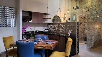 Una cocina moderna con comedor, que incluye una mesa de madera, sillas azules y amarillas, y una orquídea decorativa.
