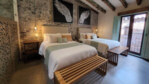 Un dormitorio con dos camas, paredes de piedra, vigas de madera y una obra de arte con alas.