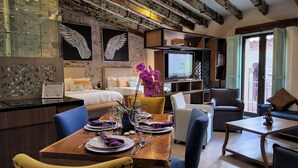 Habitación de hotel con comedor, televisión y balcón con vistas.
