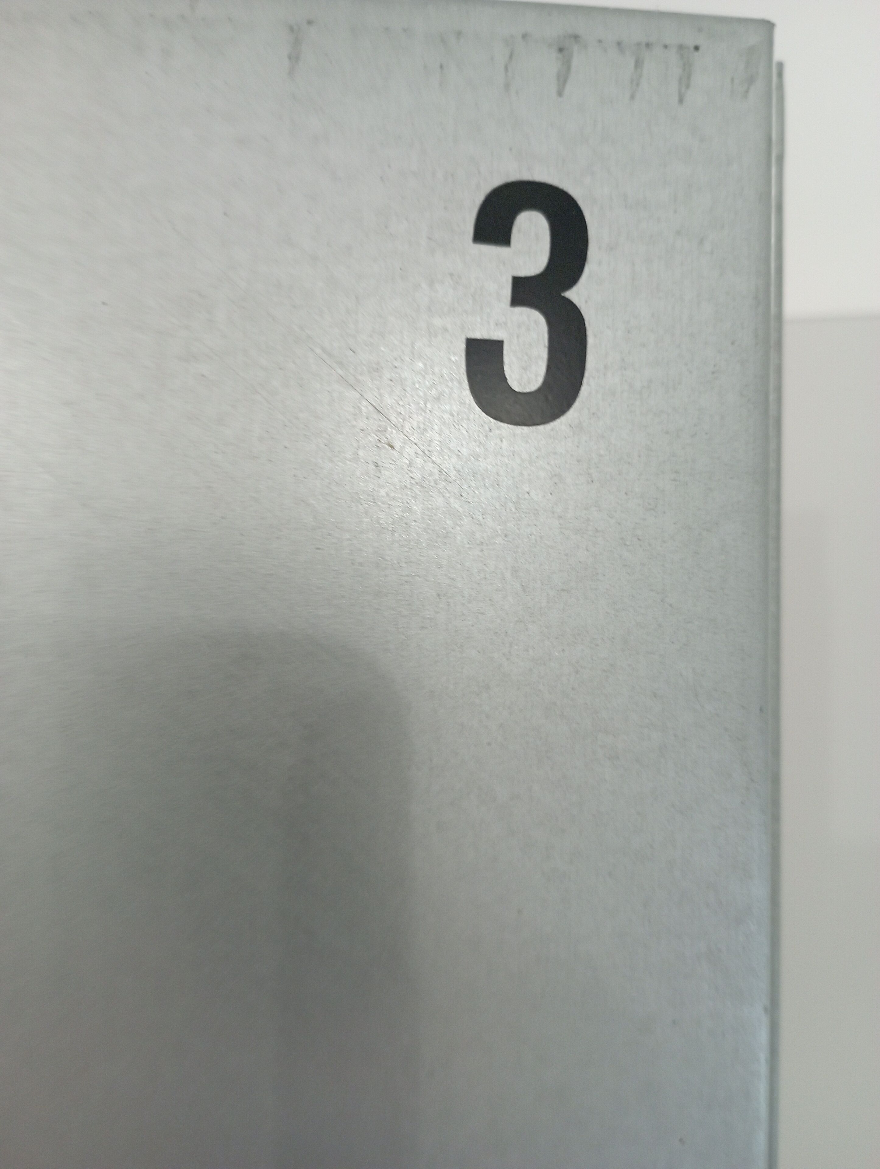 A close-up of a metallic surface with the number "3" embossed on it.