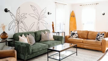 Relax in this stylish living room with a green sofa, brown leather sofa, and glass coffee table.