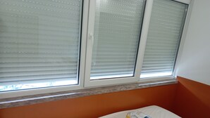 A hotel room with a bed, a window with blinds, and a package on the bed. - Home carriche 4 (Lisbon)