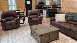 A cozy cabin interior with a living room, dining area, and kitchen.