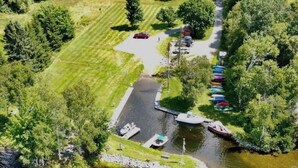 An aerial view of a lakeside property with a dock, boats, and a row of colorful canoes.