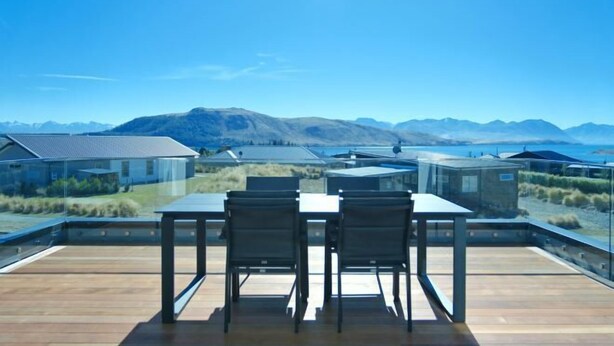 A rooftop terrace with a table and chairs, overlooking a mountainous landscape and a body of water. - Stargazing Tekapo Apartment (Lake Tekapo)