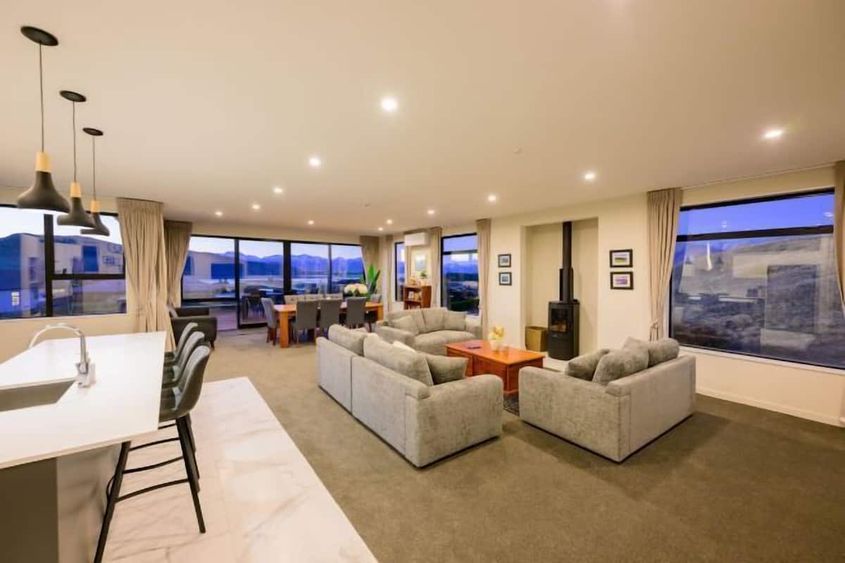 A modern living room with a sofa set, a dining area, and a kitchen island.