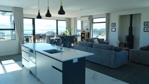 A modern living room with a large island, grey sofas, and a dining area with chairs. - Stargazing Tekapo Apartment (Lake Tekapo)