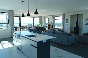 A modern living room with a large island, grey sofas, and a dining area with chairs.