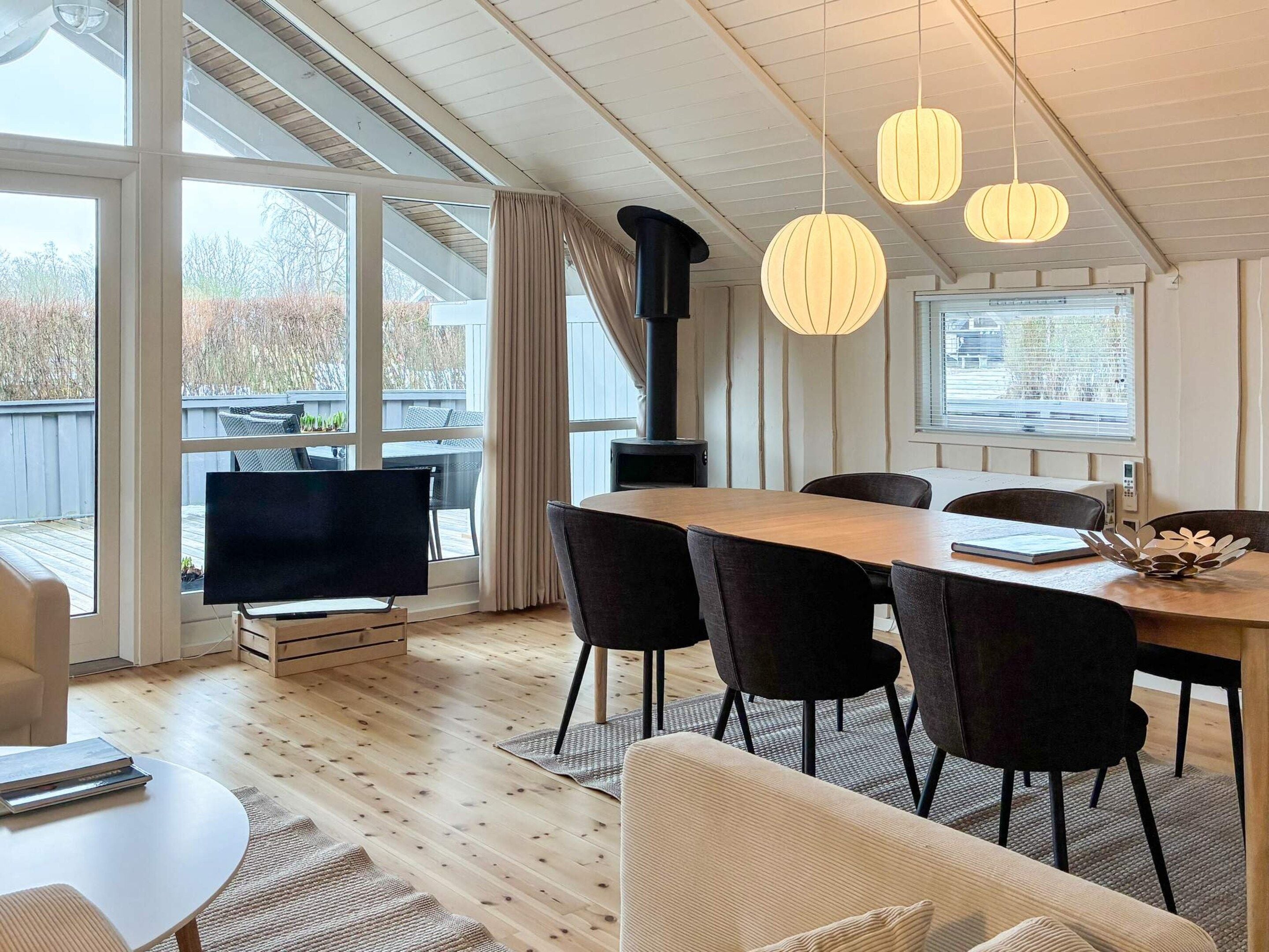 Ein moderner Essbereich mit einem Holztisch, schwarzen Stühlen und Pendelleuchten.