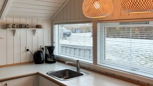 Una cocina moderna con un lavamanos, cafetera y dos lámparas colgantes.