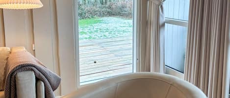 A room with a large window, a chair, and a lamp.