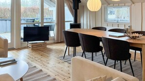 Un comedor moderno con mesa de madera, sillas negras y lámparas colgantes.