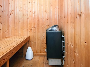 Un sauna de madera con un banco y un calentador.