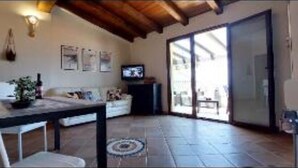 A spacious living area with a sofa, a coffee table, and a television. There is a sliding glass door leading to an outdoor area. - Maya House. (La Ciaccia)