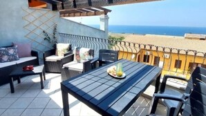 A balcony with outdoor furniture, a table with a plate of food, and a view of the sea. - Maya House. (La Ciaccia)