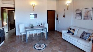 A dining area with a table and chairs, a sofa, and two wall-mounted light fixtures. - Maya House. (La Ciaccia)