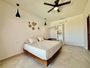 A bedroom with a bed, ceiling fan, wall decor, and built-in storage.