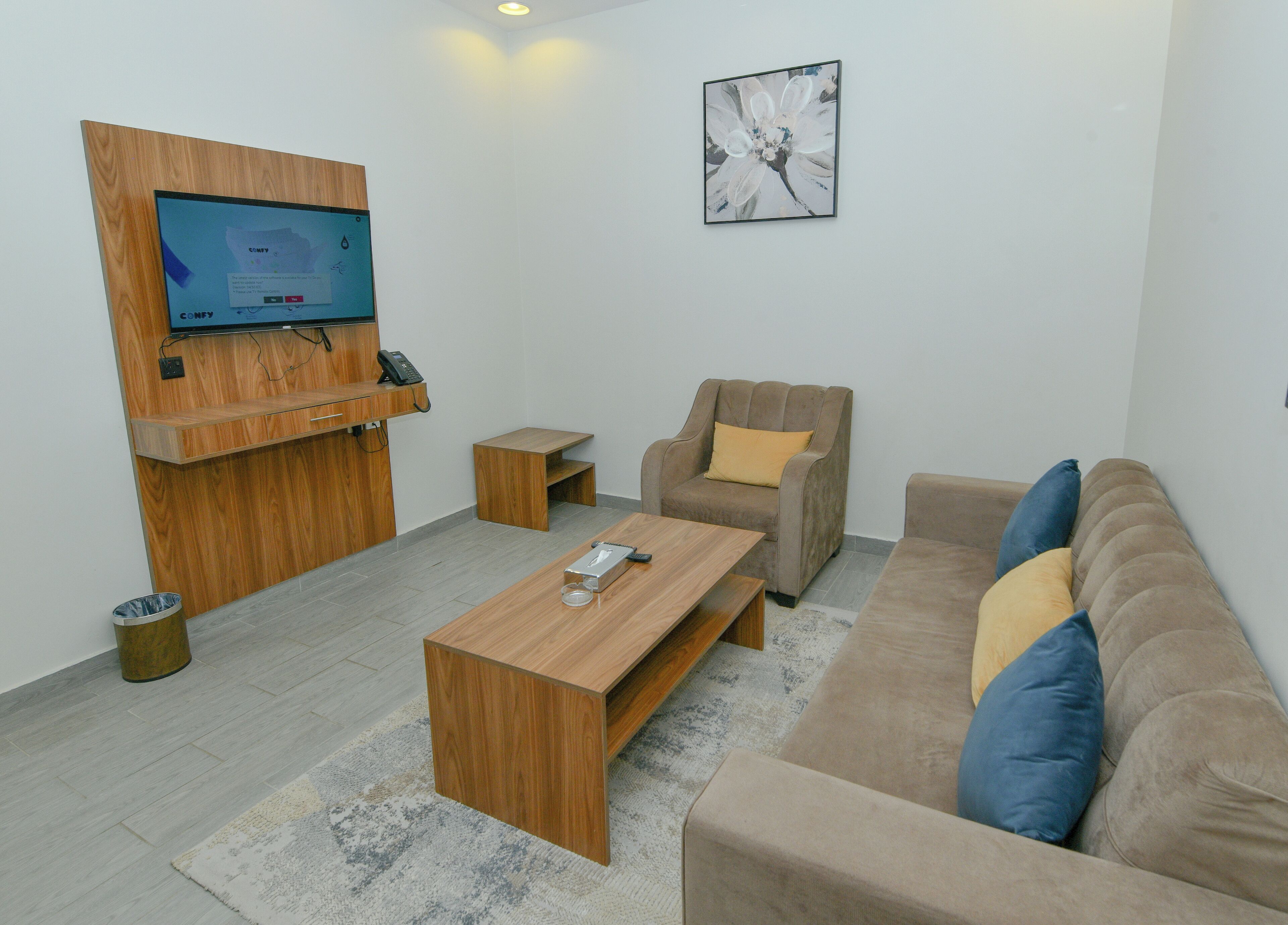Una sala de estar moderna con un mostrador de recepción de madera, un televisor de pantalla plana, un sofá cómodo, un sillón pequeño y una mesa de centro.