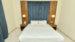 A neatly made bed with white linens, a dark headboard, and two bedside tables with lamps. - أونيسن للشقق المخدومة Onsen Serviced Apartments (Al Kharj)