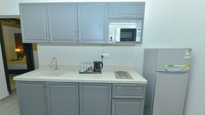 A kitchen with grey cabinets, a white countertop, a microwave, a coffee maker, and a refrigerator. - أونيسن للشقق المخدومة Onsen Serviced Apartments (Al Kharj)
