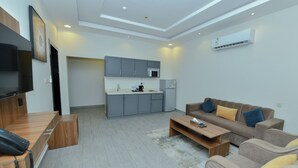 A modern living room with a sofa, coffee table, and a flat-screen TV. - أونيسن للشقق المخدومة Onsen Serviced Apartments (Al Kharj)