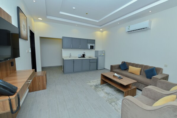A modern living room with a sofa, coffee table, and a flat-screen TV. - أونيسن للشقق المخدومة Onsen Serviced Apartments (Al Kharj)