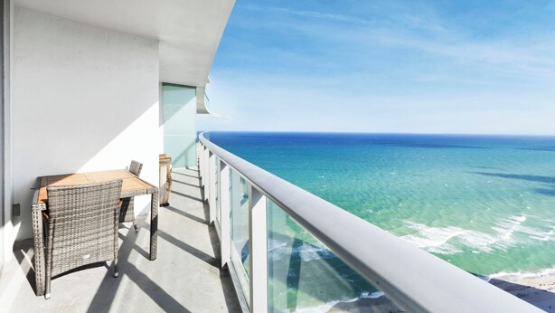 A balcony with a table and chairs, overlooking a clear blue ocean. - The Sky is the Limit: Picturesque Condo on a High Floor!!! (Hollywood)