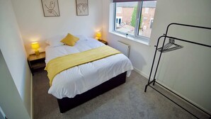 A bedroom with a bed, bedside lamps, a window, and a radiator. - Radcliffe N8 - 3 Bedroom House (Radcliffe)