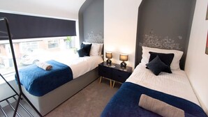 Une chambre avec deux lits, une fenêtre et une table de chevet avec des lampes.