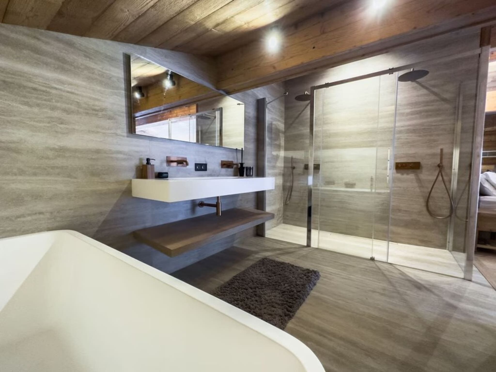 A modern bathroom with a freestanding bathtub, a vanity with a mirror, and a glass-enclosed shower area.