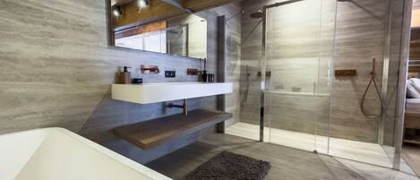 A modern bathroom with a freestanding bathtub, a vanity with a mirror, and a glass-enclosed shower area.
