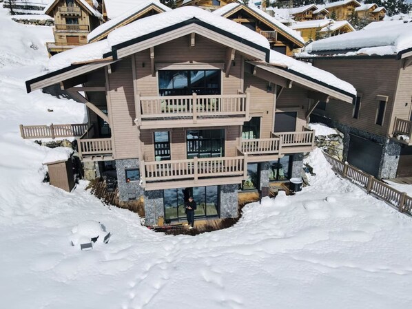 Un immeuble en bois à plusieurs étages, doté de balcons, entouré de neige.