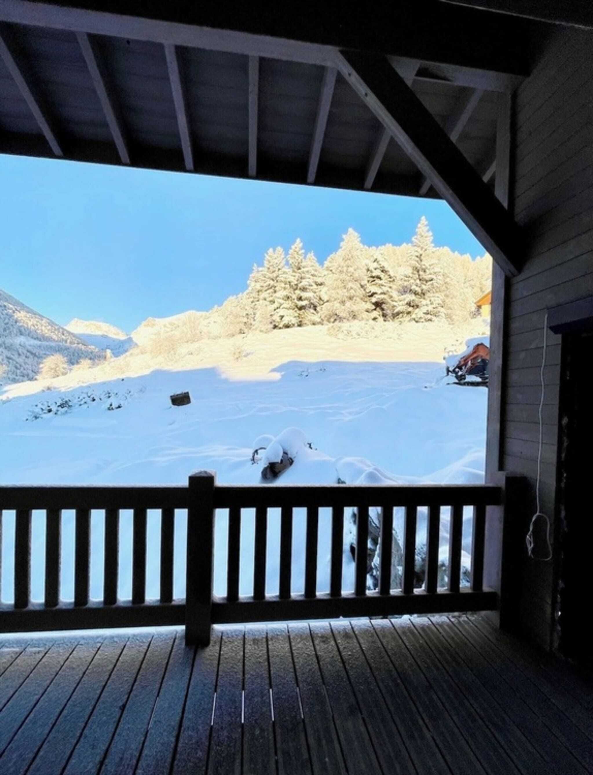 Una terraza de madera con vistas a un paisaje nevado y árboles.