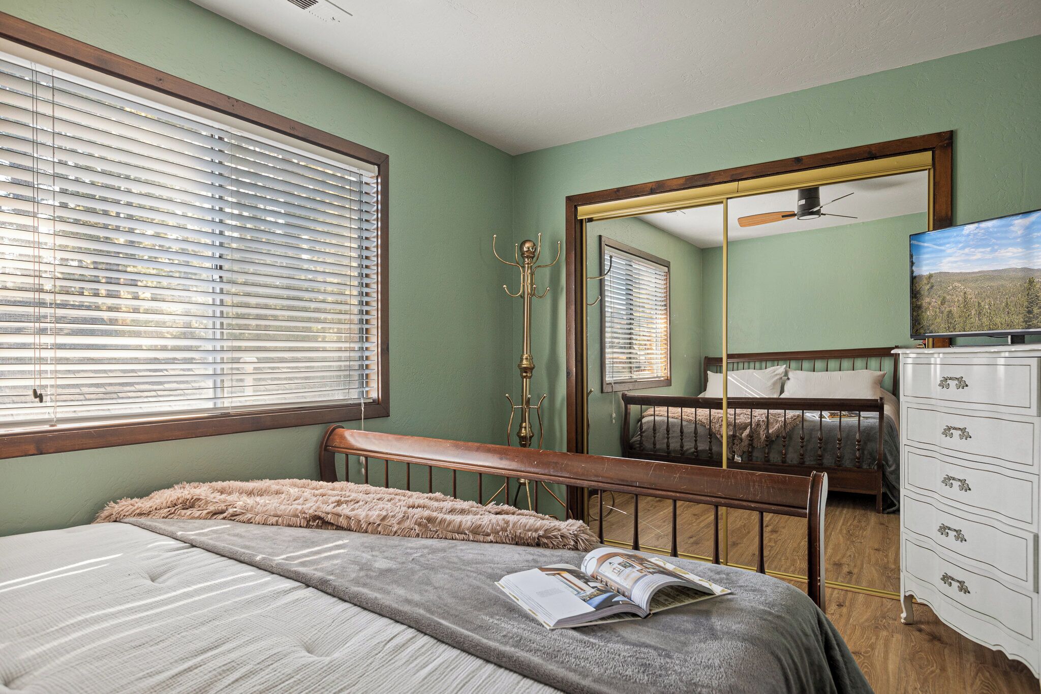 Une chambre à coucher avec un lit, une commode, un miroir et un téléviseur.