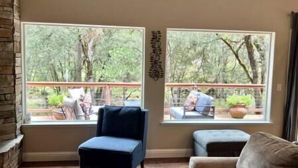 Una habitación con un ventanal grande que da a una zona boscosa, una silla pequeña y un sofá.