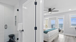A modern bedroom with a bed, a balcony with a view, and a shower area.