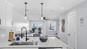 A modern kitchen with a central island, stainless steel appliances, and a view to the ocean.