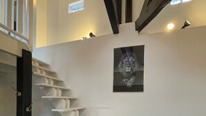 A staircase with white steps leading to a landing, a black door on the left, and a framed picture on the wall. - Luxury Apartment Atypical (Épinal)