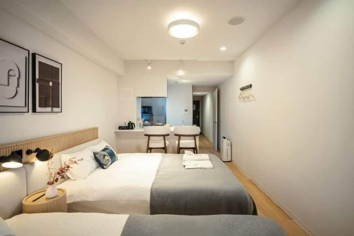 Une chambre d’hôtel avec deux lits, un bureau et une kitchenette.