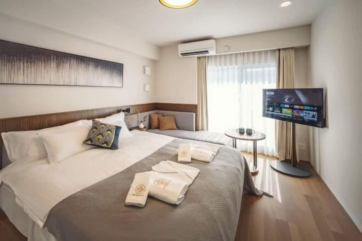 Une chambre d’hôtel avec un grand lit, une télévision, un appareil de climatisation et une petite table.
