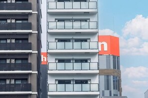 Un immeuble à plusieurs étages, sur lequel on peut voir une grande enseigne orange bien visible, placée en haut à droite.