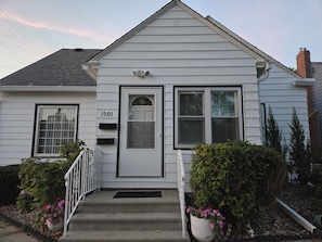 A single-story house with a white exterior, a front door, and a small porch with steps leading up to it. - Discounted Charming 2-bedroom main-level TRIPLEX in Rochester (Rochester)