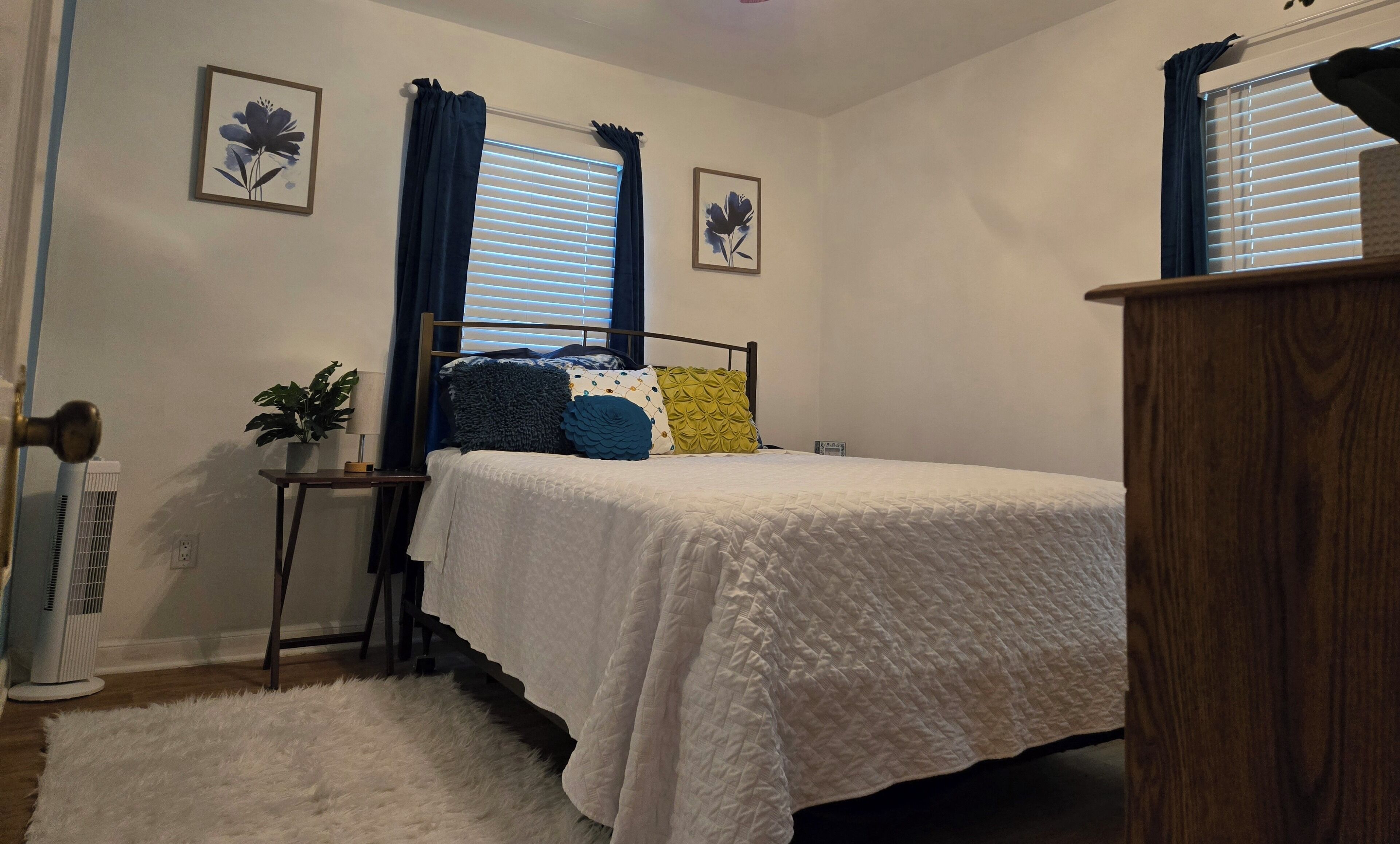 Une chambre à coucher avec un lit, une table de chevet avec une lampe, une plante en pot et un radiateur.
