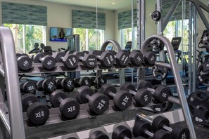 A gym with rows of dumbbells and weight plates, large windows, and exercise equipment. - 5BR to Gather, Relax and Make Memories (2640ST) (Kissimmee)