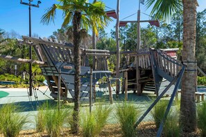 A wooden play structure with rope bridges and a slide, surrounded by palm trees and greenery. - 5BR to Gather, Relax and Make Memories (2640ST) (Kissimmee)