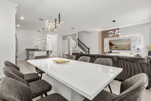 A modern kitchen with white cabinetry, a central island, and pendant lighting. - 5BR to Gather, Relax and Make Memories (2640ST) (Kissimmee)