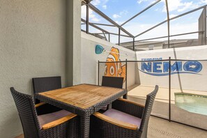 An outdoor patio area with a table and chairs, a mural, and a pool. - 5BR to Gather, Relax and Make Memories (2640ST) (Kissimmee)