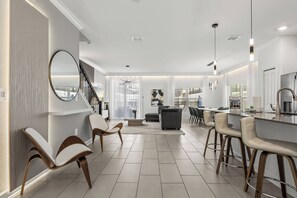 A modern kitchen with a bar area, a dining space with chairs, and a staircase leading to an upper level. - 5BR to Gather, Relax and Make Memories (2640ST) (Kissimmee)