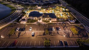 An aerial view of a hotel with a large parking lot, multiple buildings, and a swimming pool area.